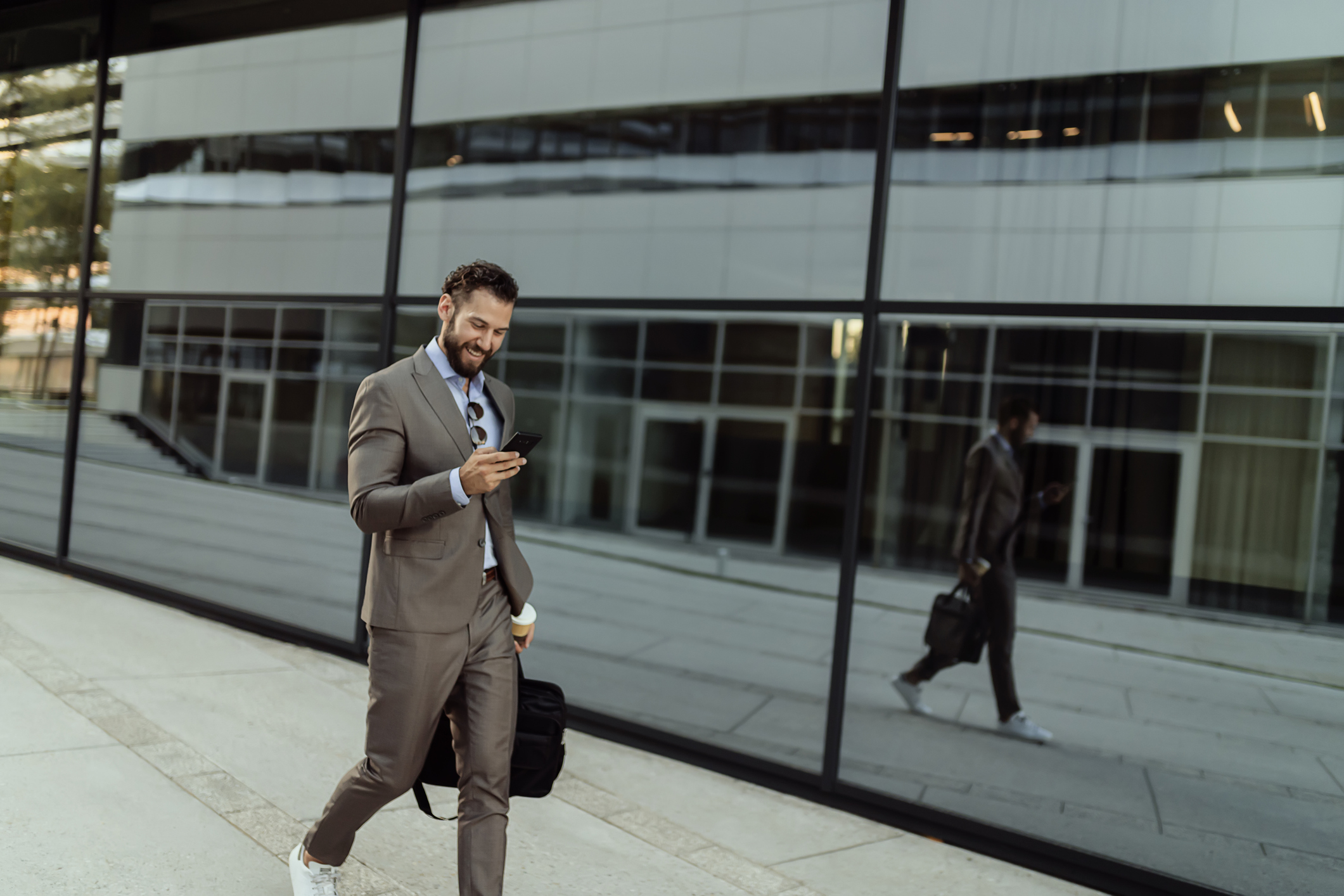 Geschäftsmann vor Bürogebäude blickt auf sein Smartphone